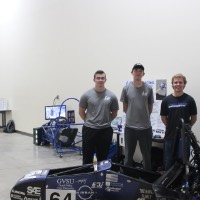 Four students standing next to a solar car.